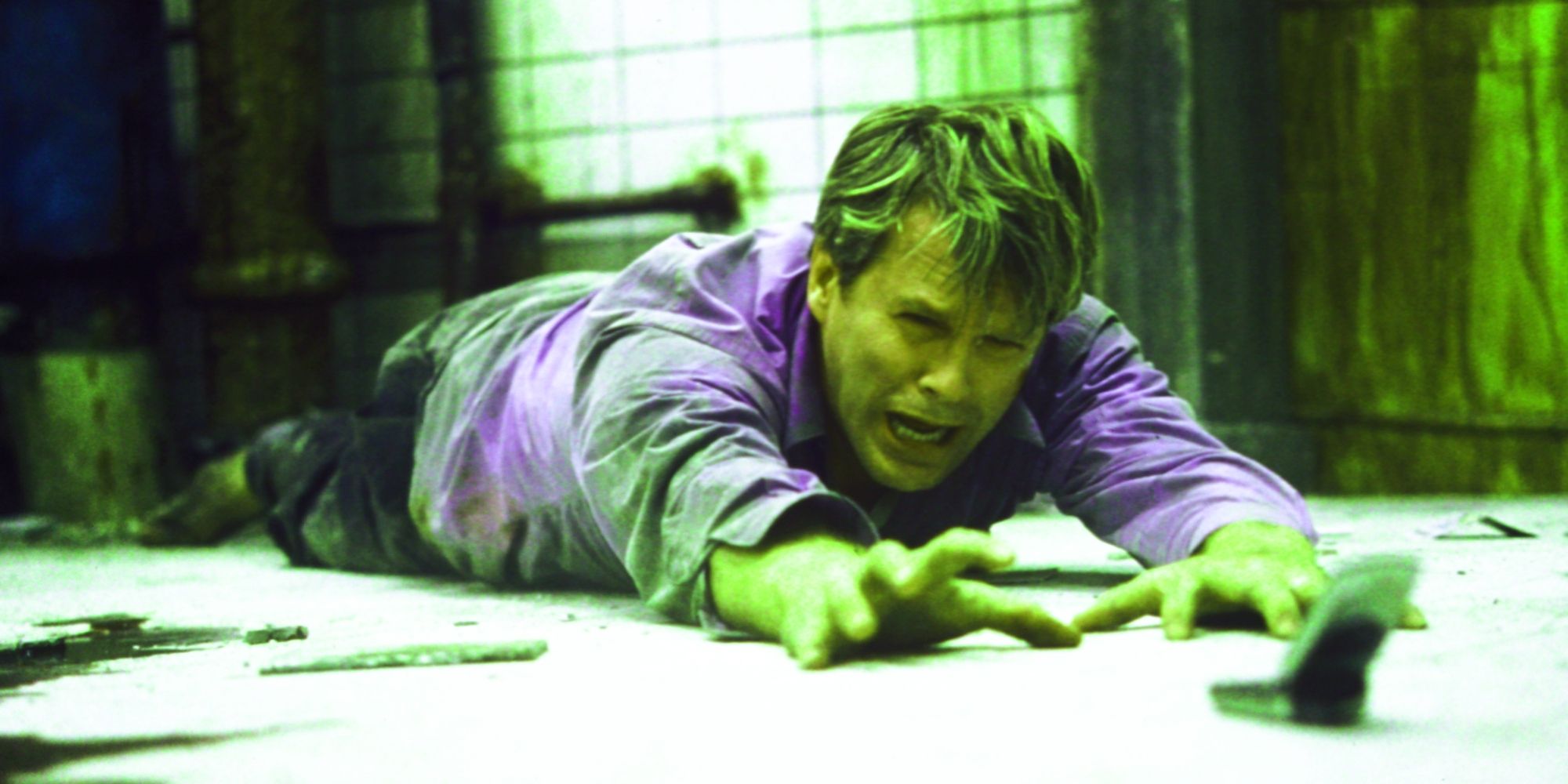 Dr. Gordon, played by actor Cary Elwes, stretched out on the floor reaching for a cellphone in Saw.