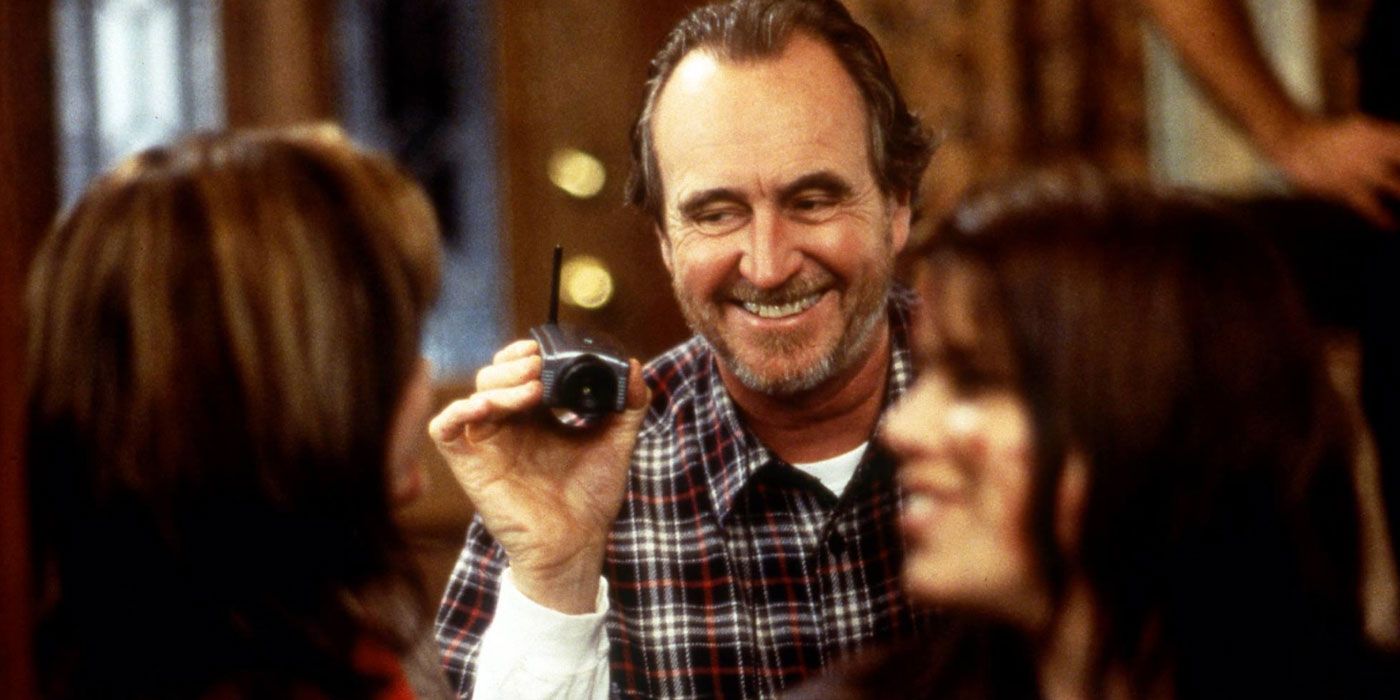 Director Wes Craven smiles while holding a small camera on the set of Scream.