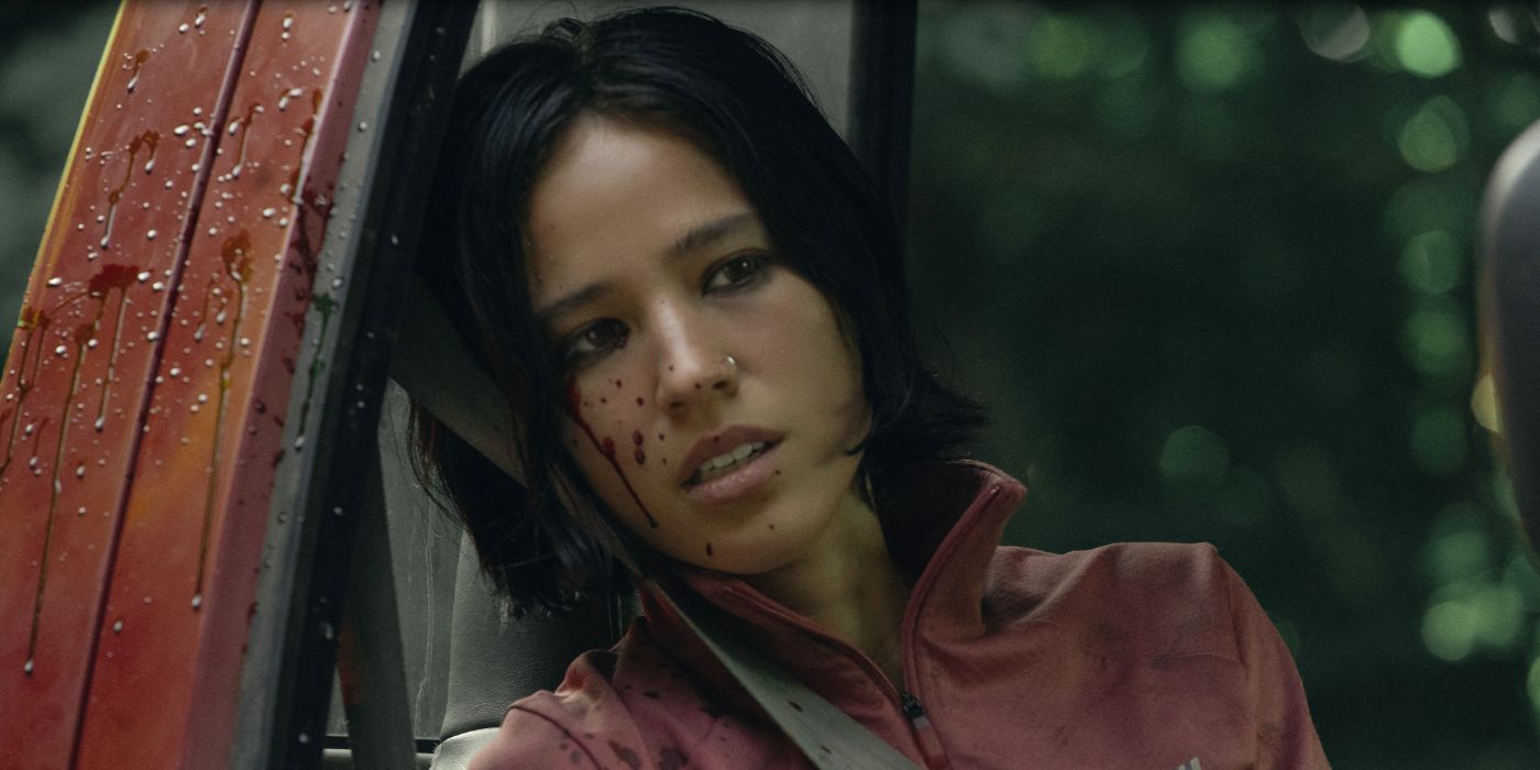 Kelsey Asbille as Iris, sitting in a red truck with blood splattered on her face in Netflix's Don't Move