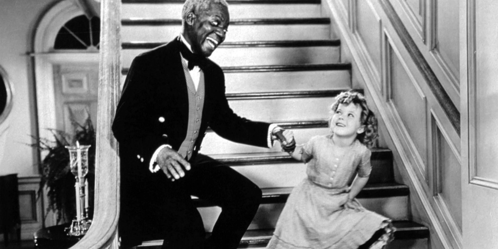 Shirley Temple holding Bill Robinson's hand while dancing on a staircase in The Little Colonel (1935)