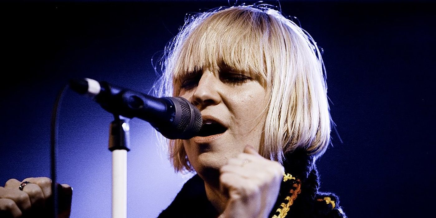 Sia in front of a microphone singing.