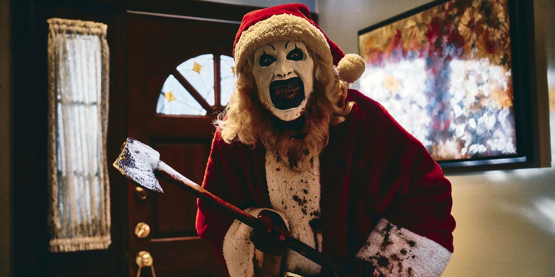 Art the Clown walks through a house with a bloody ax in 'Terrifier 3'