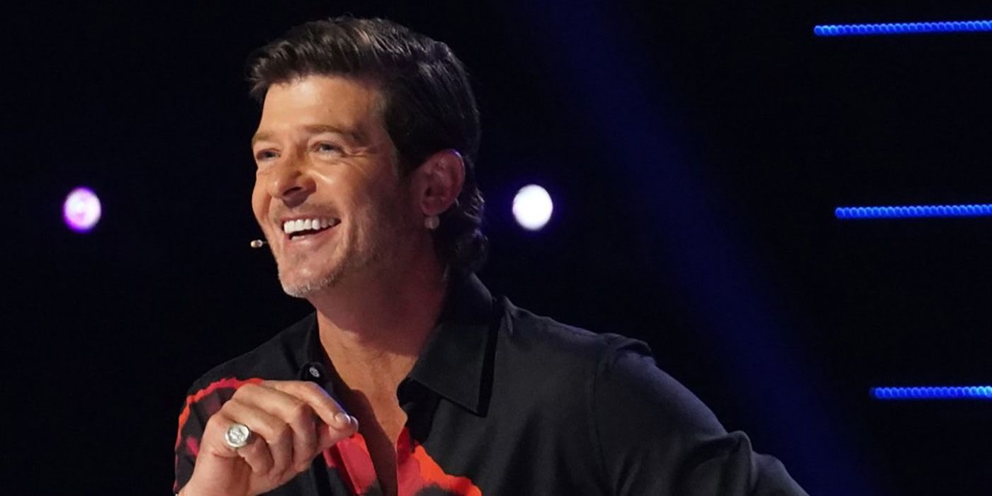 Robin Thicke smiling, sitting on the judges panel on the Masked Singer.