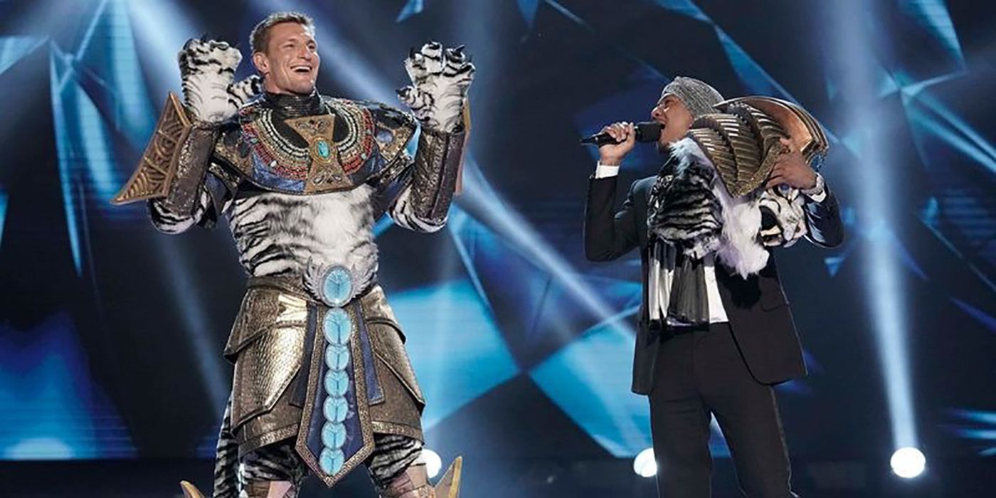 Rob Gronkowski with the hood off his costume smiling and talking to Nick Cannon on The Masked Singer.