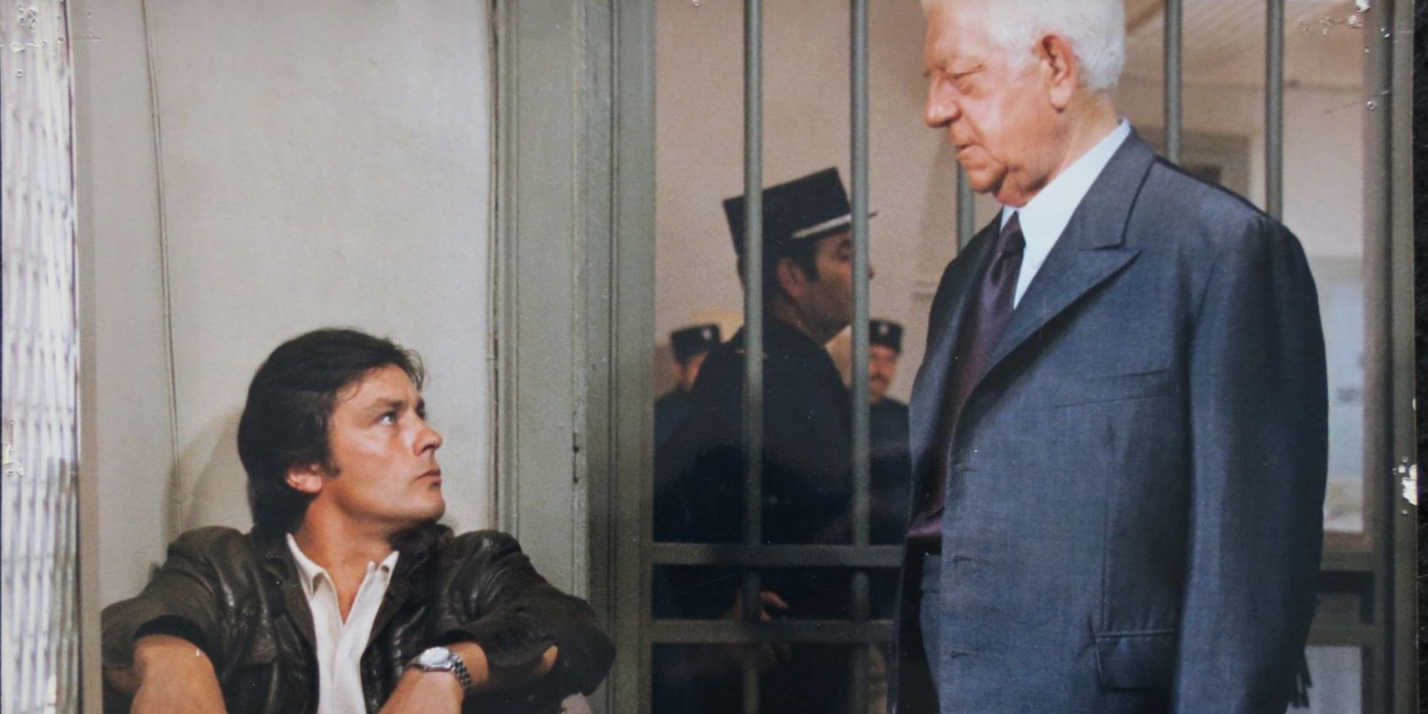 Alain Delon sits in a jail cell looking up at another man in Two Men in Town - 1973