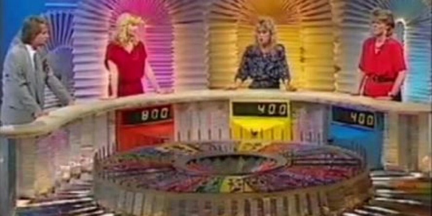 Players stand around the big wheel as Pat Sajak talks to them in Wheel of Fortune.