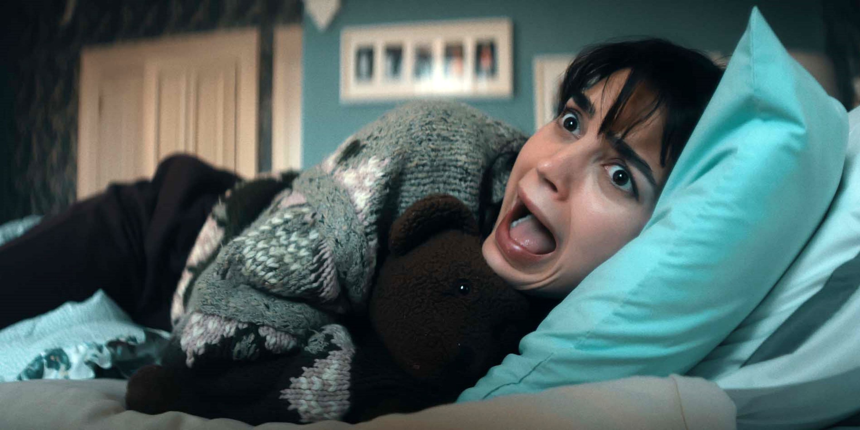 Melissa Barrera lying on her side in bed while screaming in Your Monster