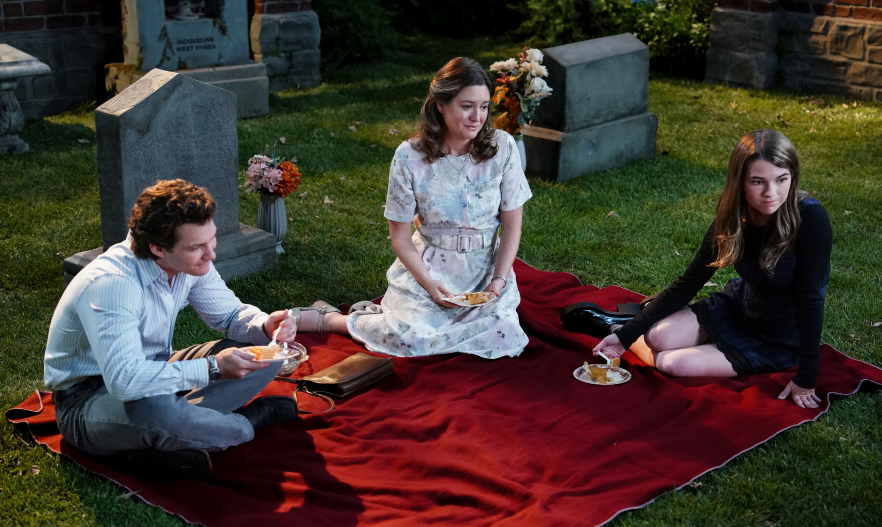 Georgie, Missy, and Mary Cooper visit George Senior's grave sitting on a picnic blanket