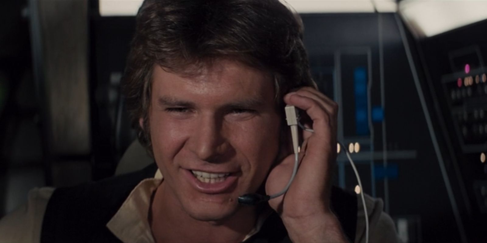 Han Solo, played by Harrison Ford, smiles while holding an earpiece in 'Star Wars: Episode IV – A New Hope'.