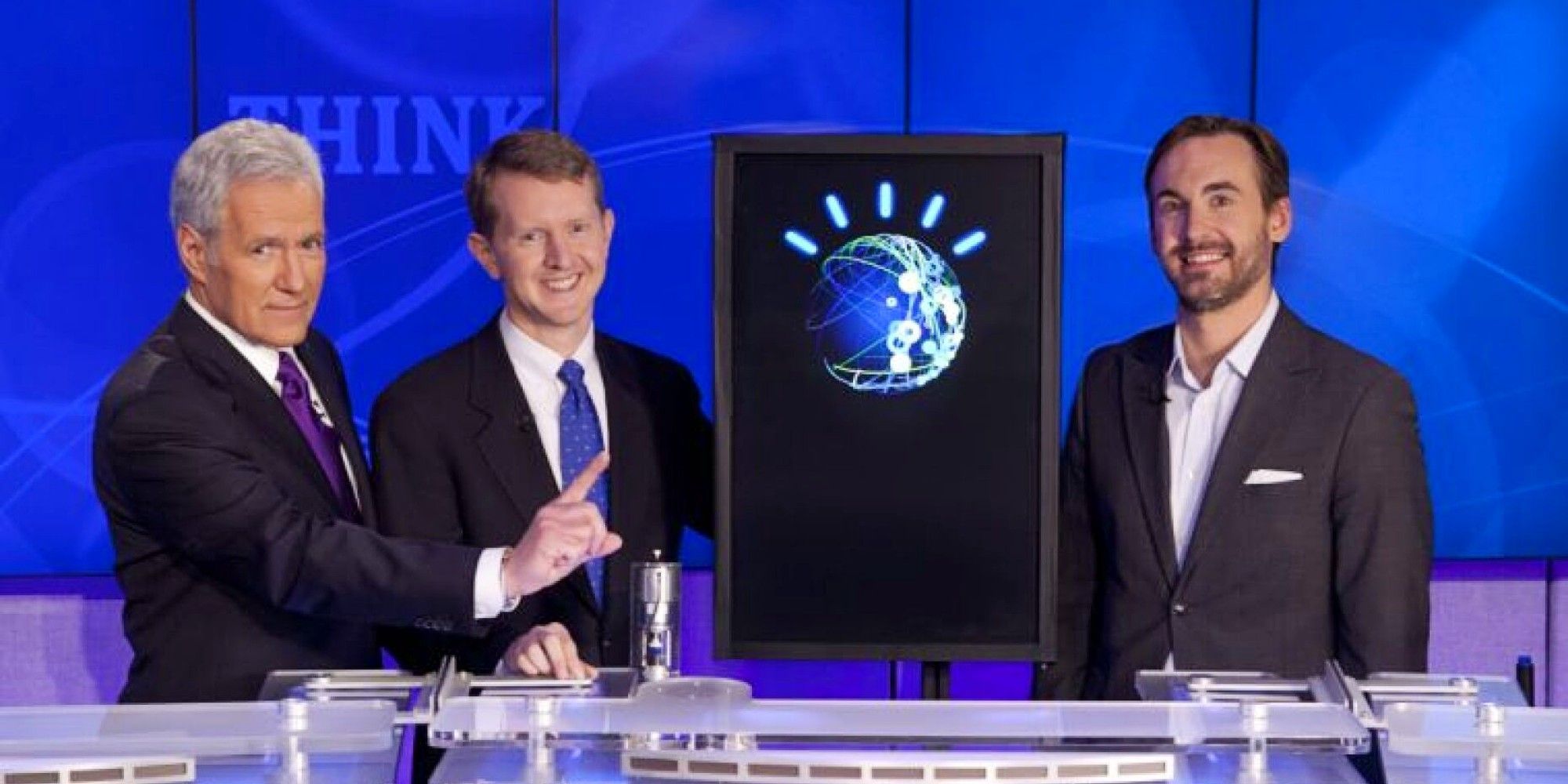 Alex Trebek, Ken Jennings, Watson the robot, and Brad Rutter standing together on Jeopardy!