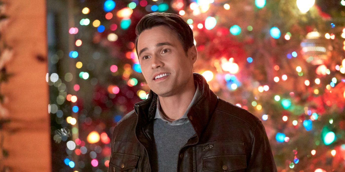 Brett Dalton in front of Christmas trees with lots of multicolored lights in Once upon A Christmas Miracle.