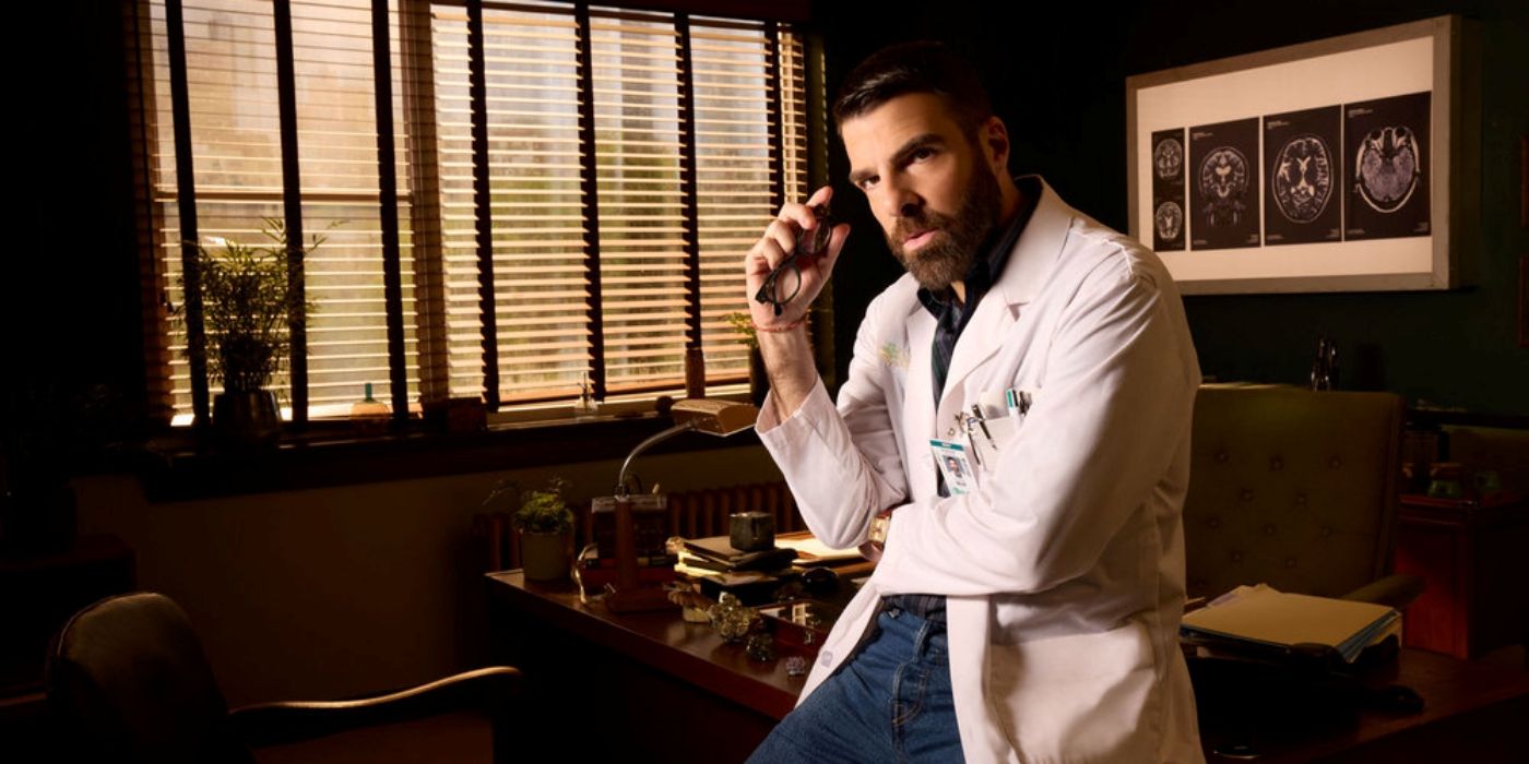 Zachary Quinto as Dr. Oliver Wolf leaning against the desk in his office in Brilliant Minds