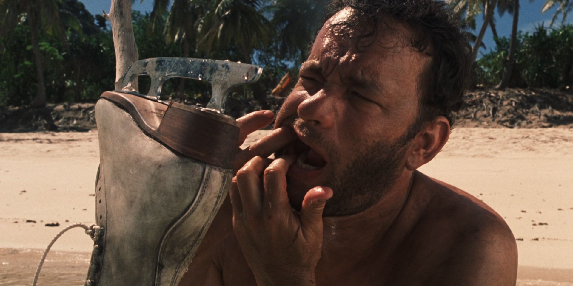 Chuck Noland, played by Tom Hanks, looks at his teeth, reflected by an ice skate, in 'Cast Away'.