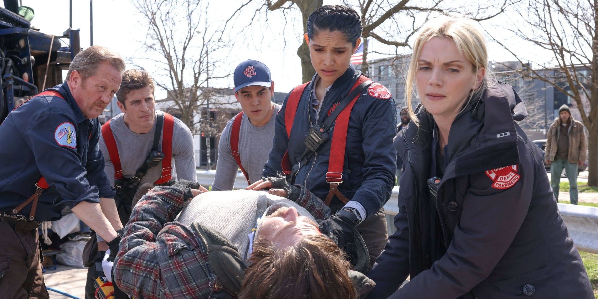 The cast of Chicago Fire stand around a man on a stretcher