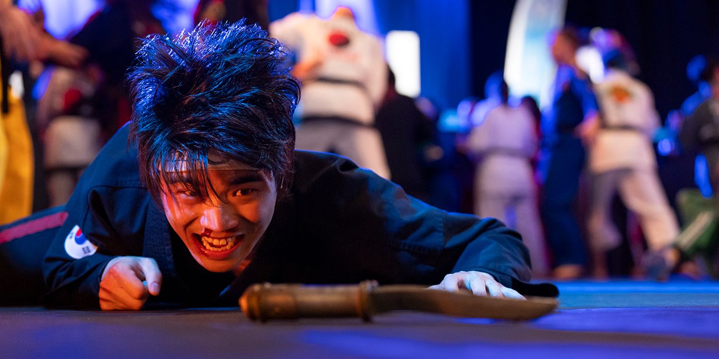 Brandon H. Lee as Kwon looking at Kreese's dagger on the ground during the Sekai Taikai