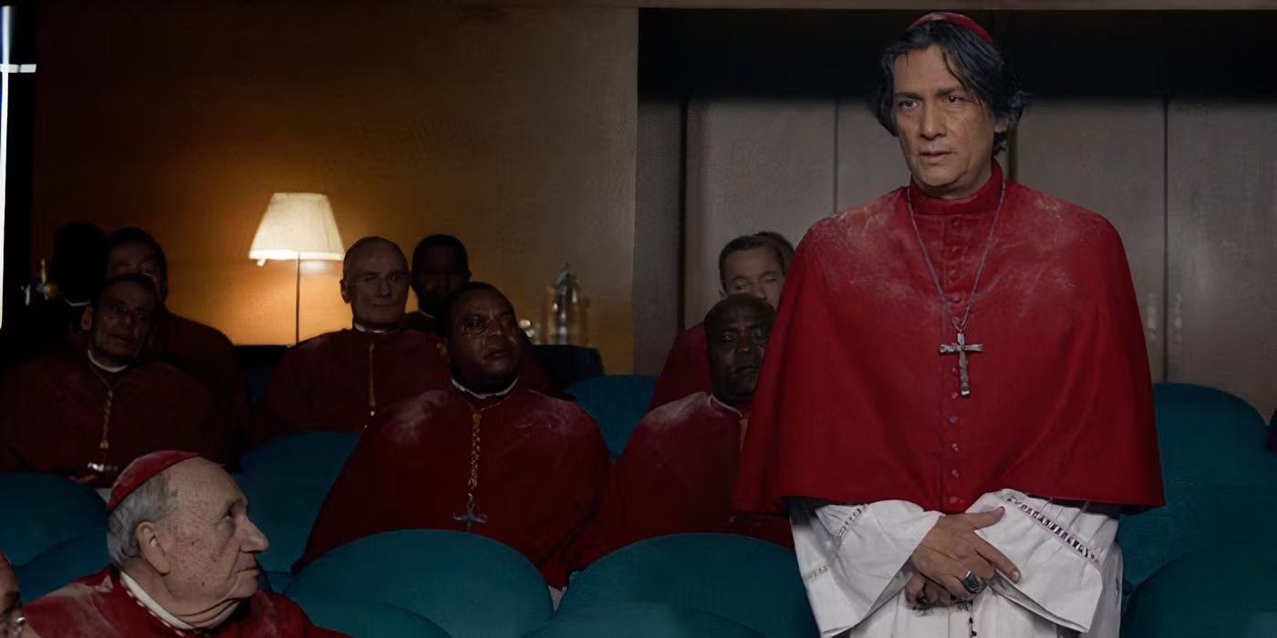 Carlos Diehz as Vincent Cardinal Benitez giving a speech to the other bishops while they are all covered in dust and soot in 'Conclave' 