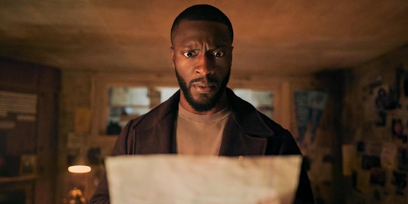 Aldis Hodge as Alex Cross looking shocked and confused, holding a photo in Cross.