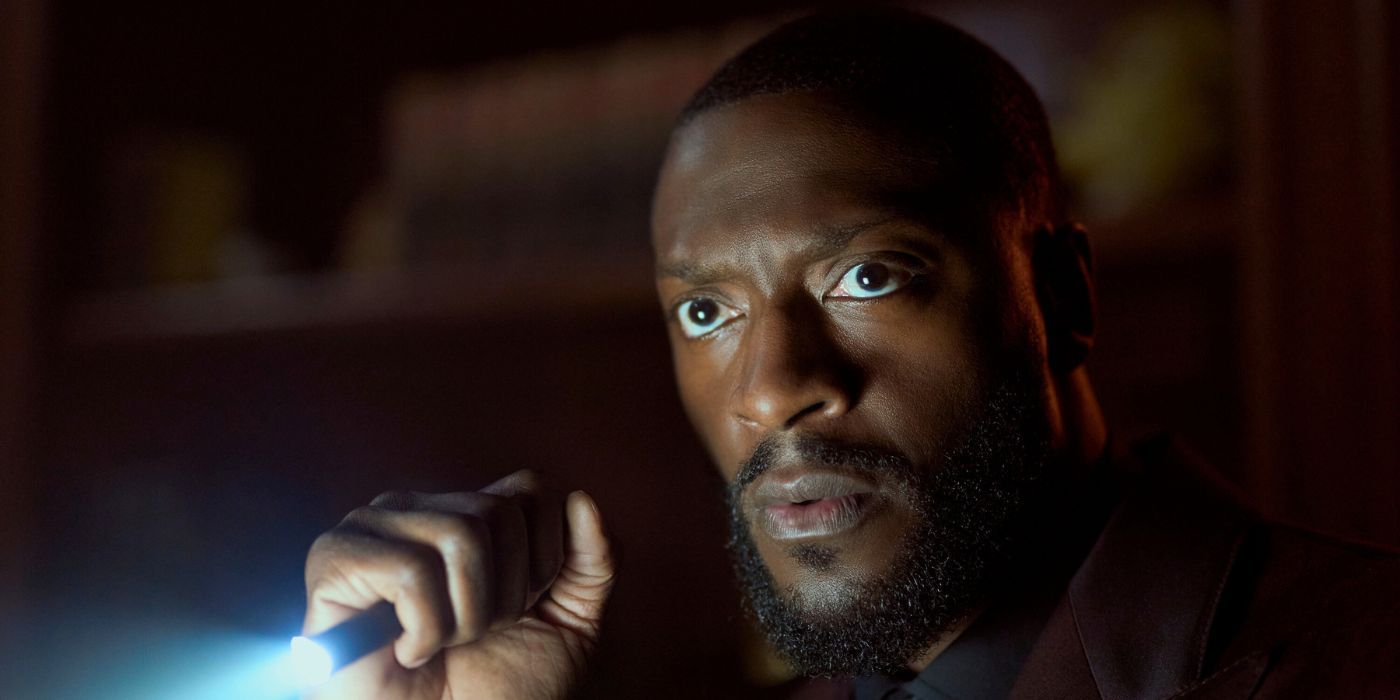 Aldis Hodge as Alex Cross, shining a flashlight in Cross.