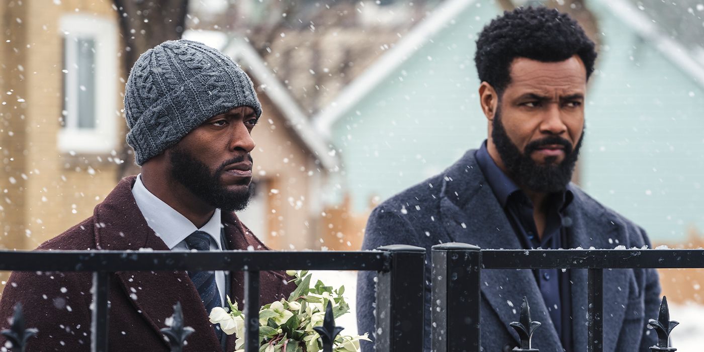 Cross (Aldis Hodge) and Sampson (Isaiah Mustafa) standing behind a gate with somber expressions