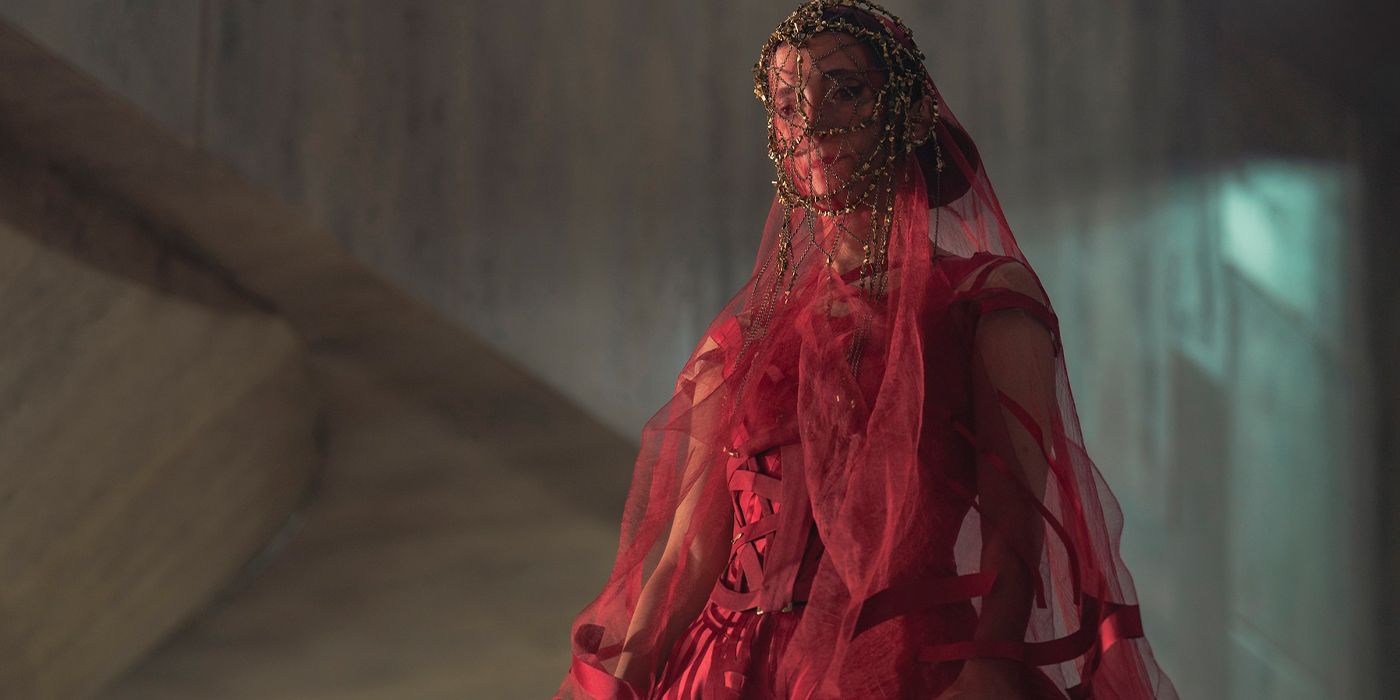 Ynez (Sarah-Sofie Boussnina) in a red dress and veil looking down