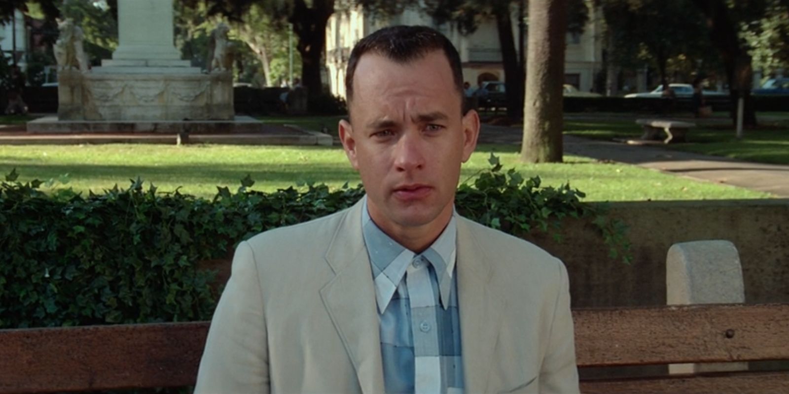 Forrest Gump, played by Tom Hanks, sits on a bench and stares ahead in 'Forrest Gump'.