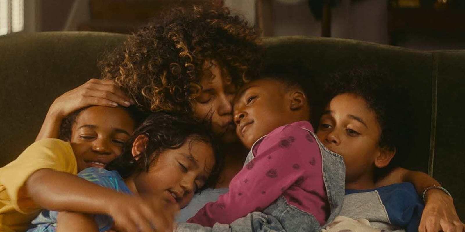 Halle Berry as Millie Dunbar hugging a group of four children on the couch in 'Kings' (2017)