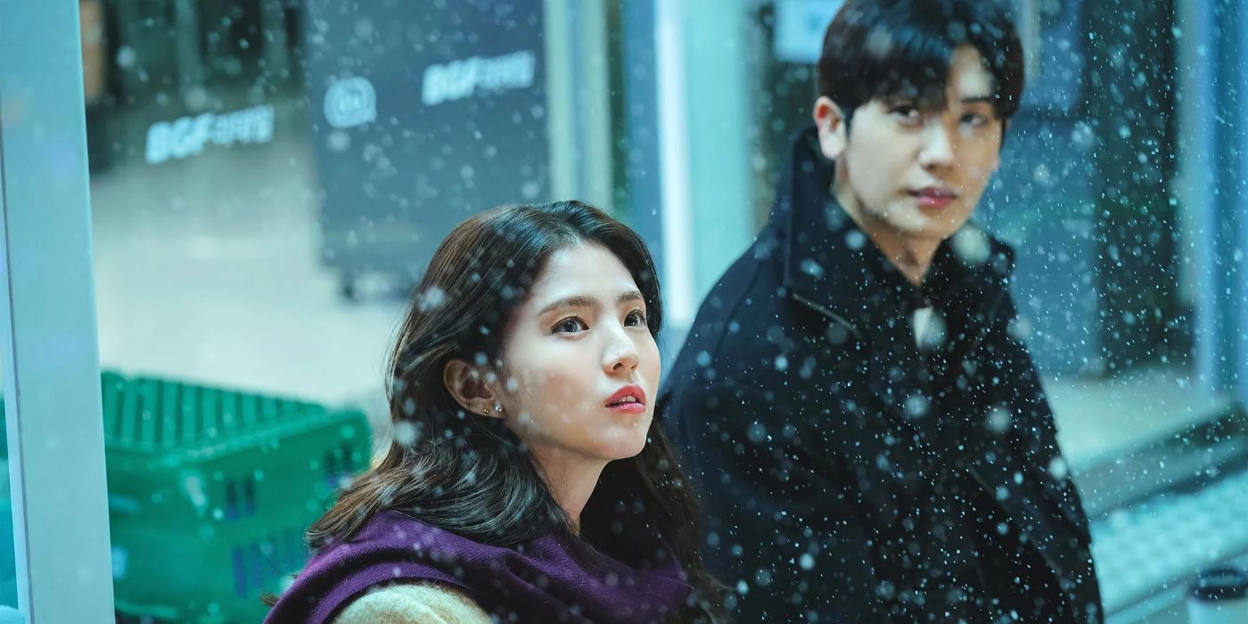 Han So-hee and Park Hyung-sik sitting on a bench outside and looking at falling snow in Soundtrack #1.