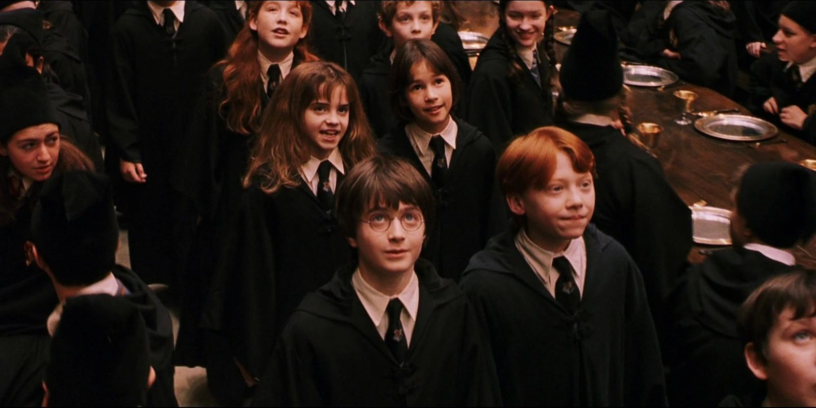 Hermione (Emma Watson) talking to Pansy (Katherine Nicholson) as they enter the Great Hall behind Harry (Daniel Radcliffe) and Ron (Rupert Grint) in Harry Potter and the Sorcerer's Stone