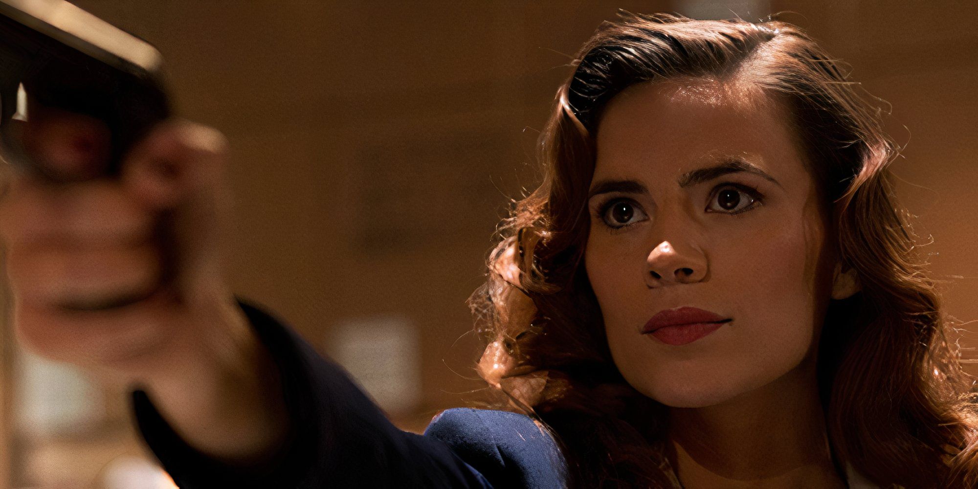 Hayley Atwell pointing a gun at someone as Peggy Carter in Agent Carter