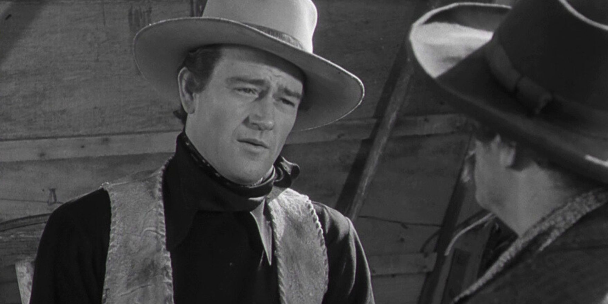 John Wayne as Bob Seton talking to someone standing in front of him in Dark Command (1940)