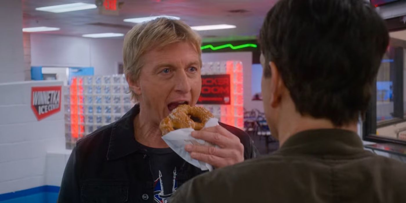 Johnny Lawrence eats a pretzel in Danny LaRusso's face in Cobra Kai.