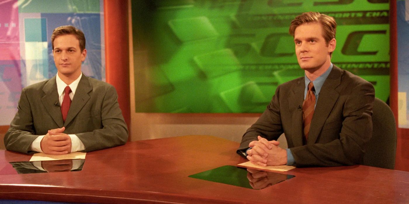 Josh Charles and Peter Krause wear suits as they sit at the anchor news desk