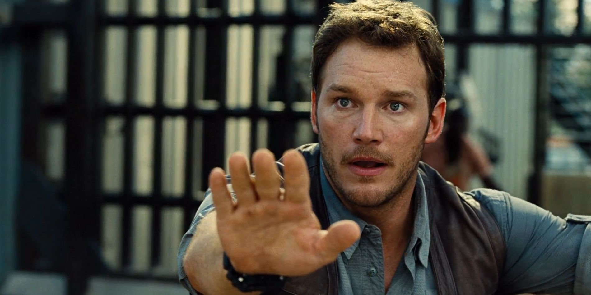 Owen Grady, played by Chris Pratt, extends a hand directly in front of him in 'Jurassic World'.