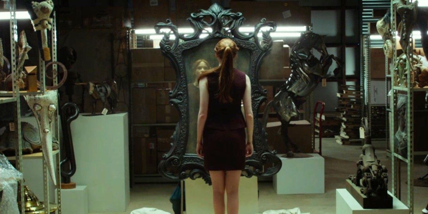 Karen Gillan se encuentra frente a un gran espejo con un ornamentado marco Oculus negro.