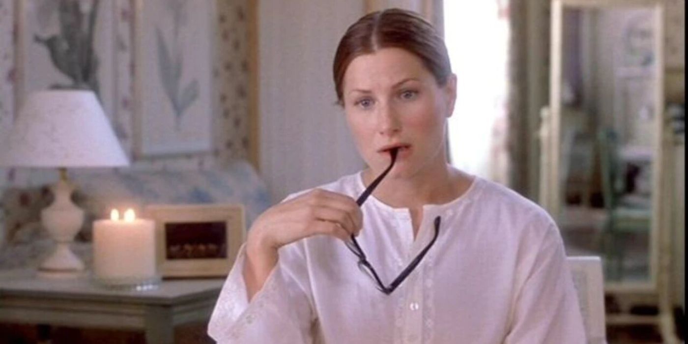 Kathryn Hahn playing Michelle, sitting on a couch and biting a pair of glasses in How To Lose A Guy In 10 Days