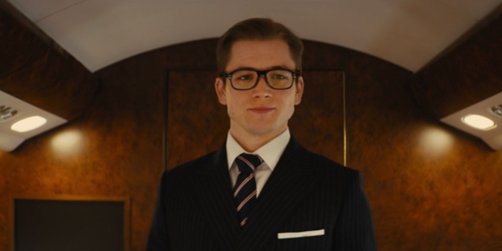 Eggsy, played by Taron Egerton, smiles in his new suit in &lsquo;Kingsman: The Secret Service&rsquo;.