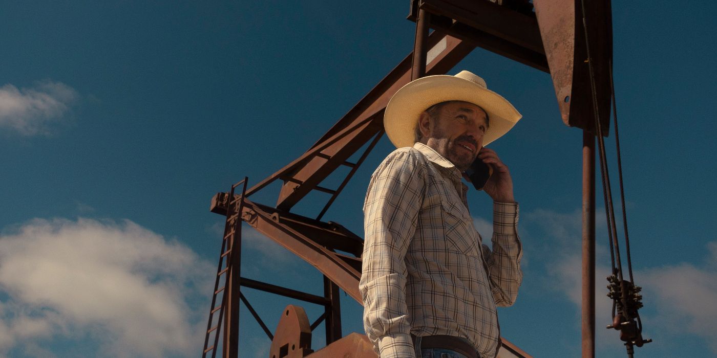 Tommy Norris (Billy Bob Thornton) talks on his phone, standing in front of oil rig equipment in Landman.