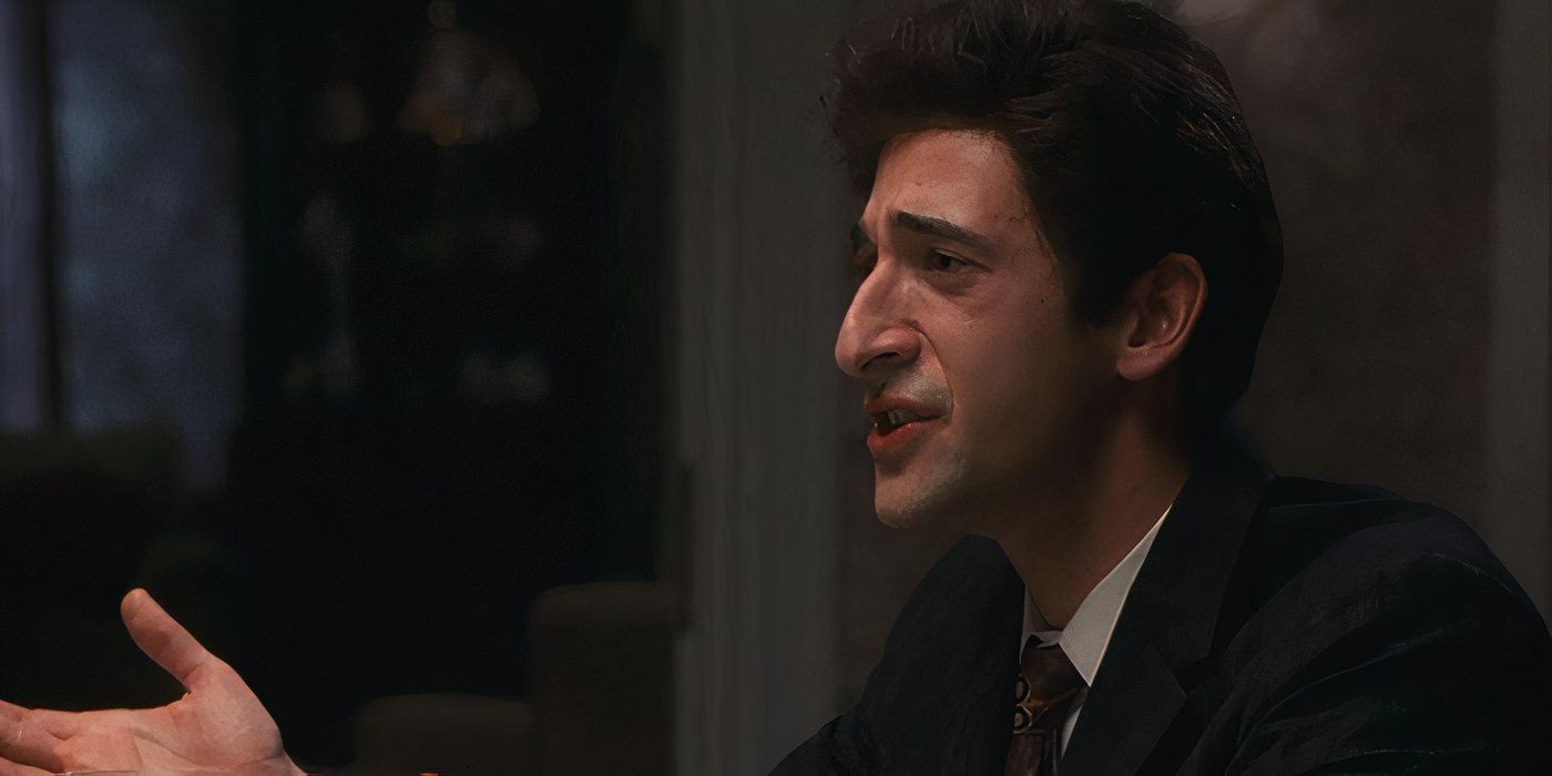 Adrien Brody wears a suit and tie and sits at a table talking to someone off camera in Liberty Heights.