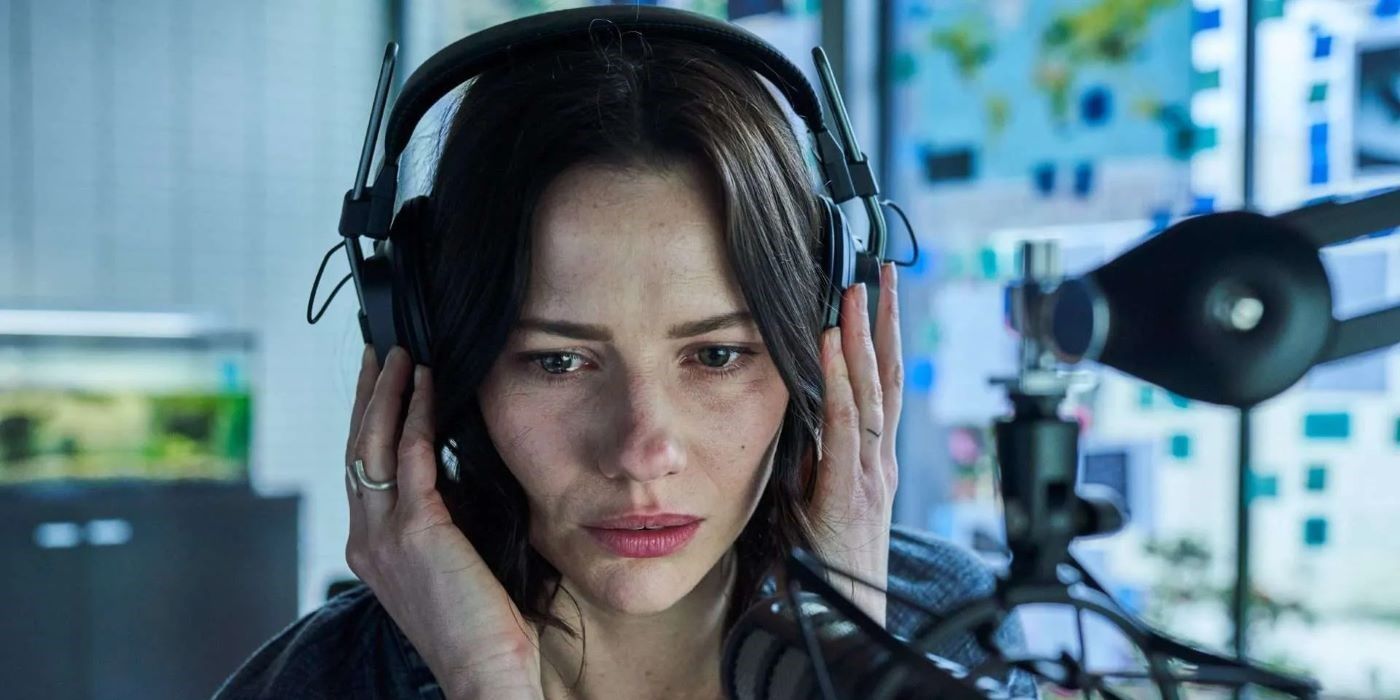 Lily Sullivan holding her headphones closer to her ears in Monolith