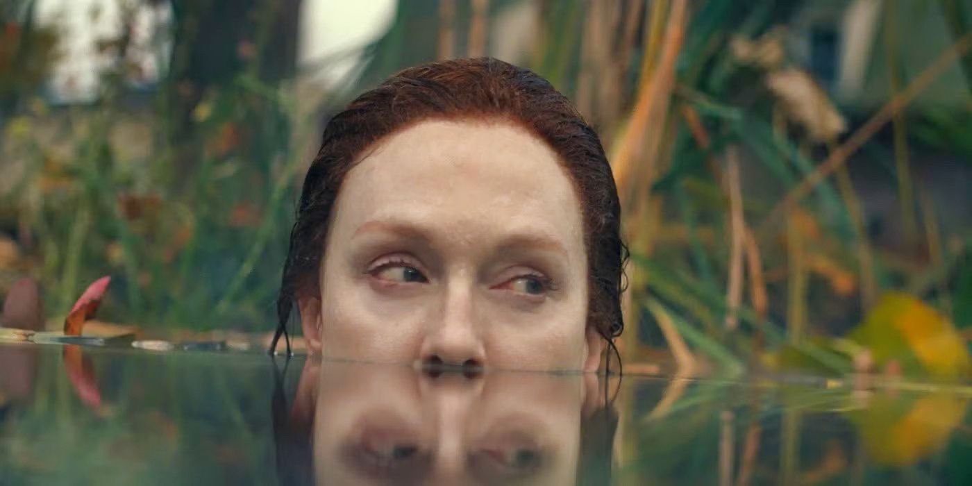 Julianne Moore in a lake with the top of her head above the water, looking to the side