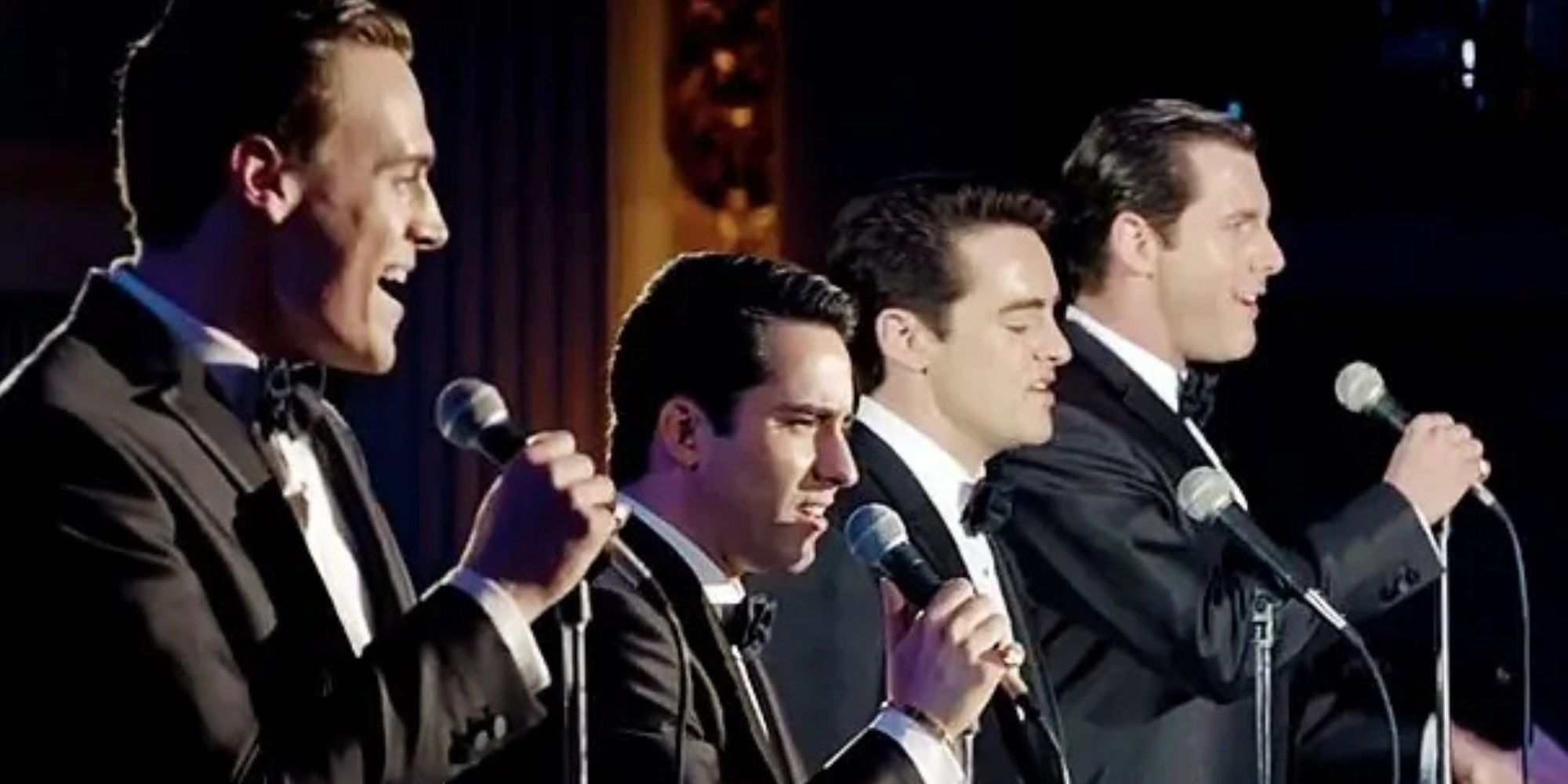 Michael Lomenda, John Lloyd Young, Vincent Piazza, Erich Bergen standing in a line together singing into microphones on stage in Jersey Boys (2014)