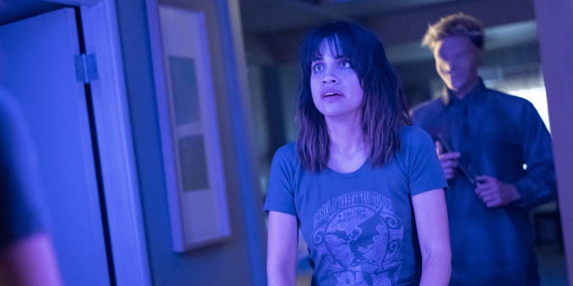 Natalie Morales stares at a mirror with a mysterious masked man behind her in Room 104.