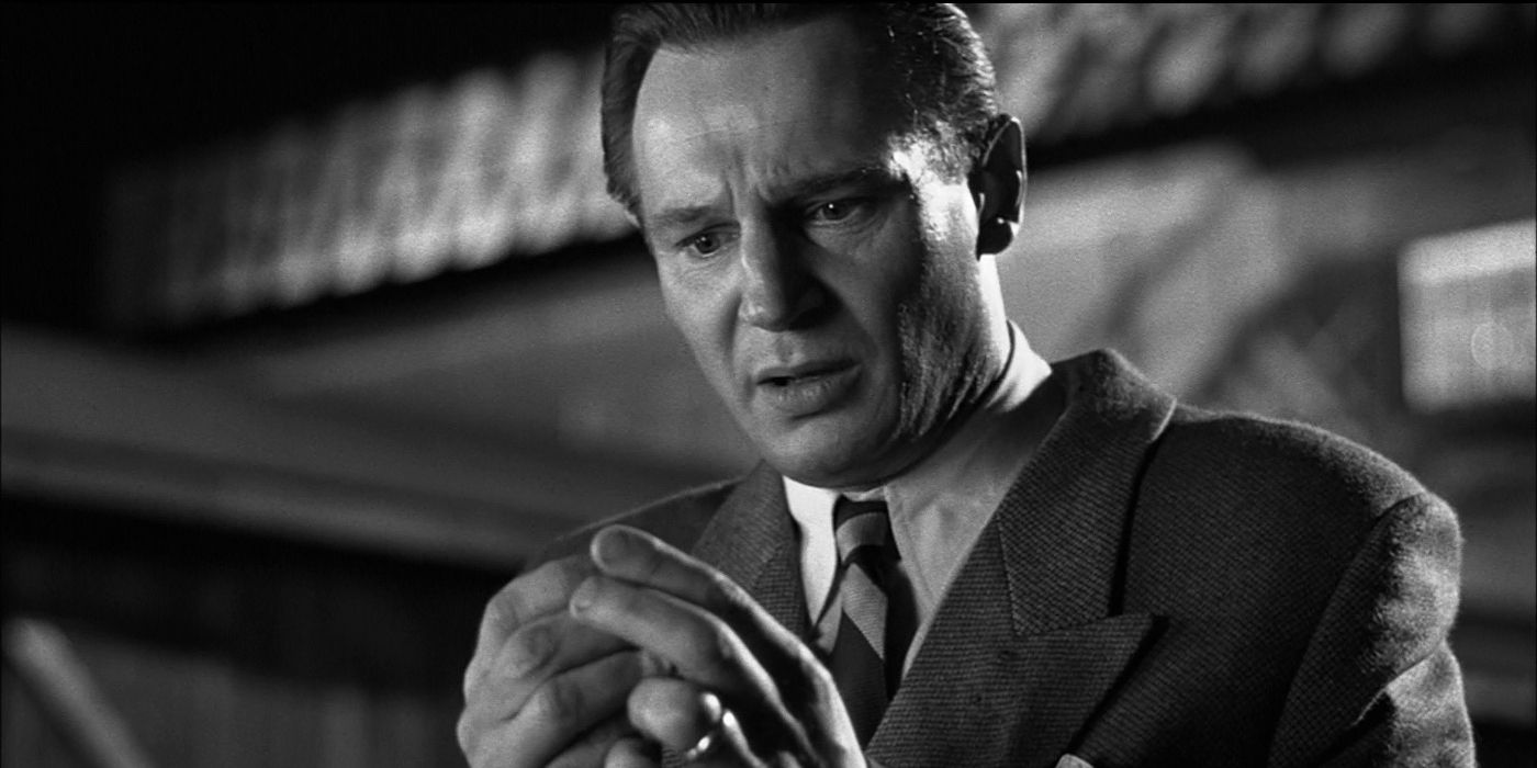 Oskar Schindler (Liam Neeson) holds an object and looks distraught in Schindler's List (1993).