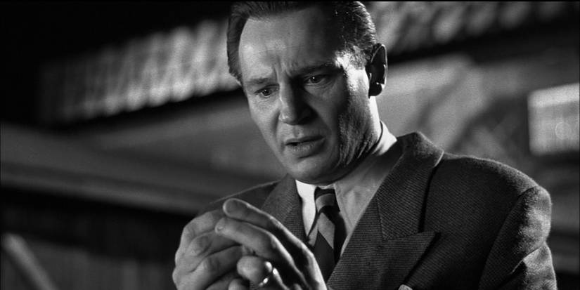 Oskar Schindler (Liam Neeson) holds an object and looks distraught in Schindler's List (1993).