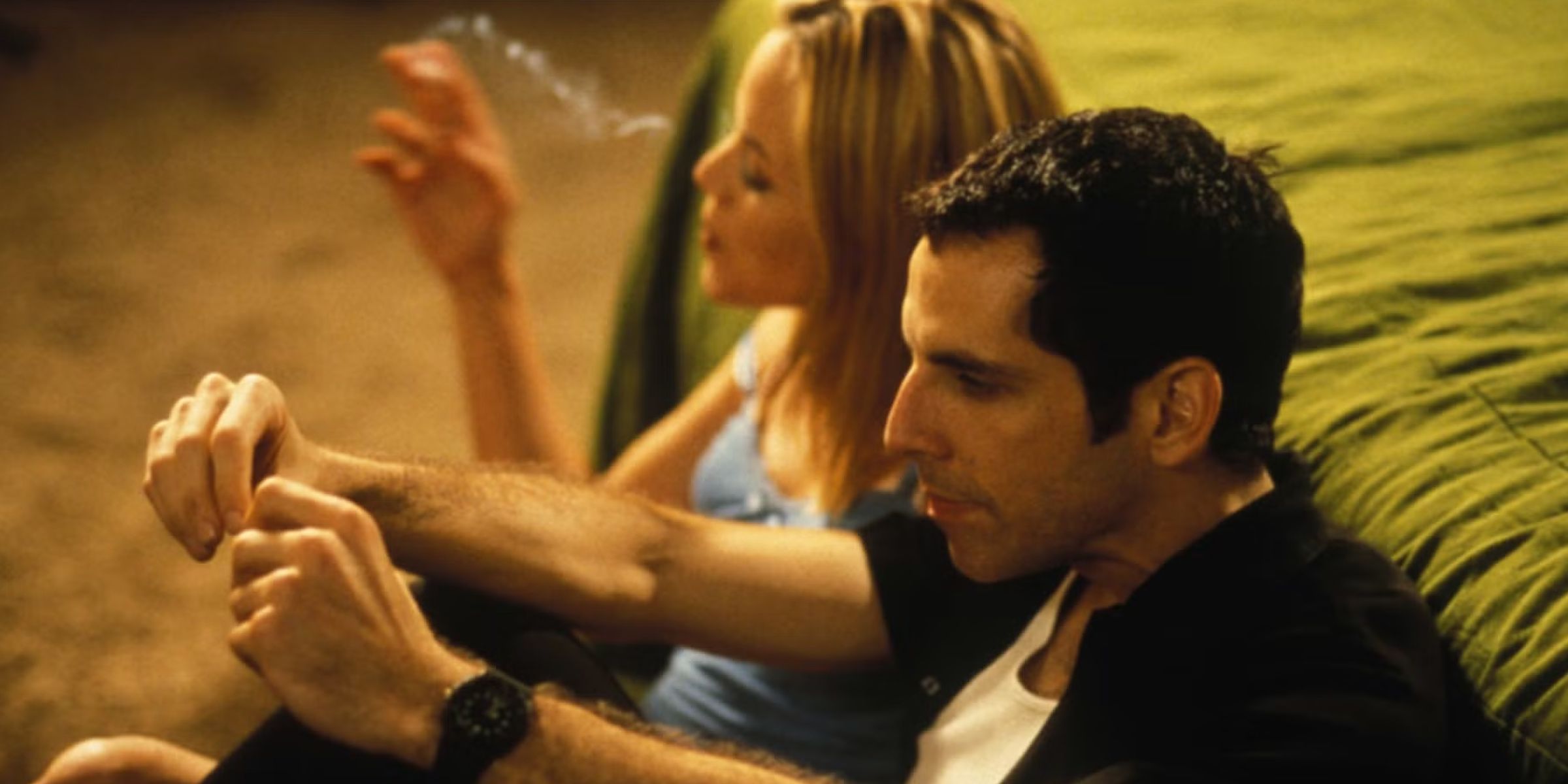 Ben Stiller as Jerry Stahl and Maria Bello as Kitty smoke while leaning against a bed in 'Permanent Midnight'