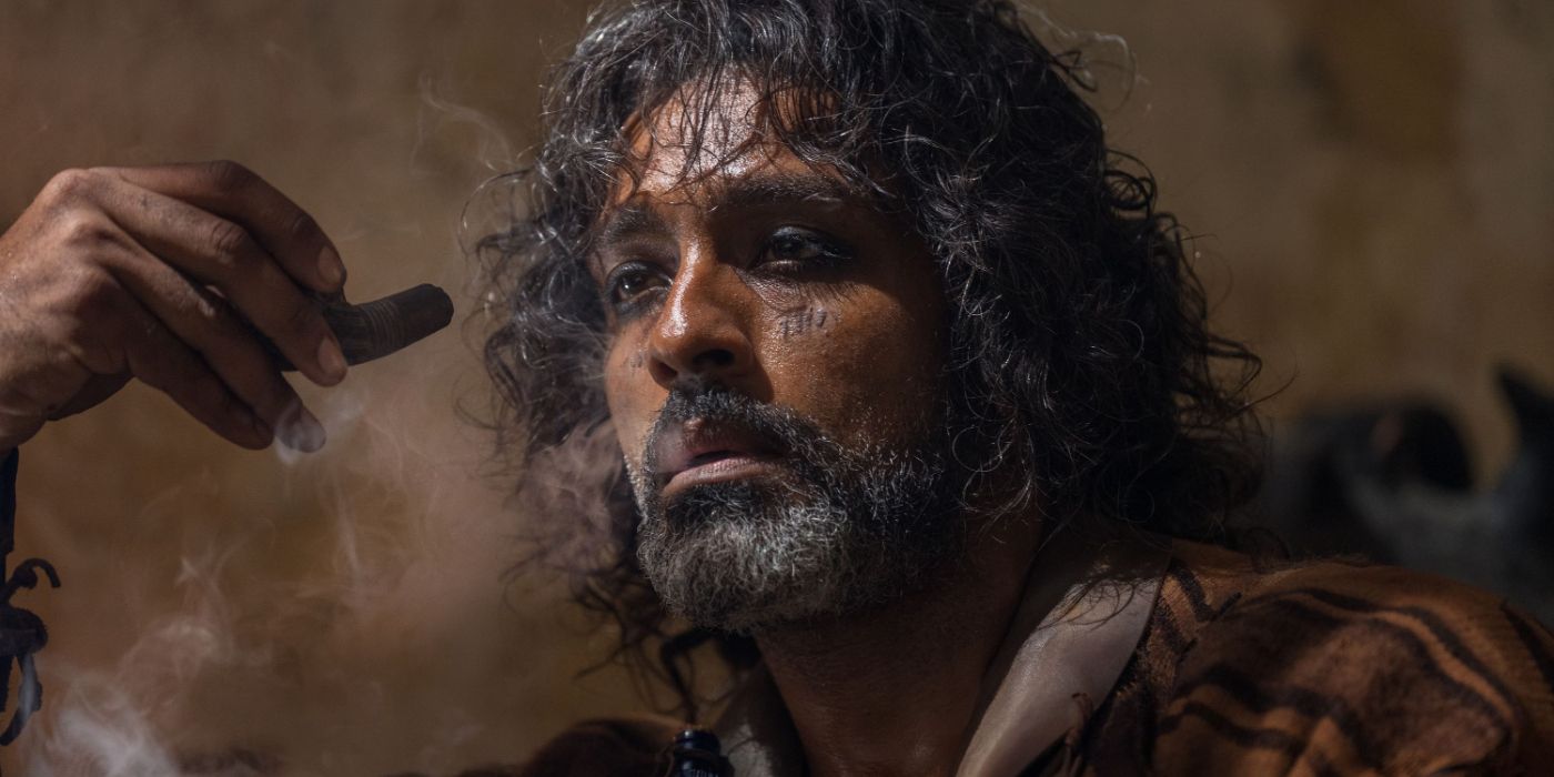 A close up of Ravi holding a pipe and smoking in a scene in &lsquo;Gladiator II&rsquo;