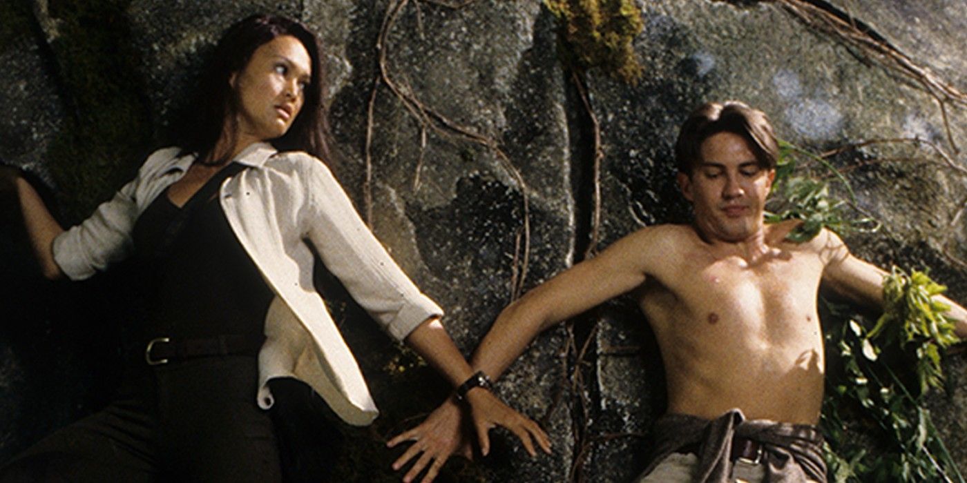 Tia Carrere y Christian Anholt de Relic Hunter están presionados contra una pared y preocupados.