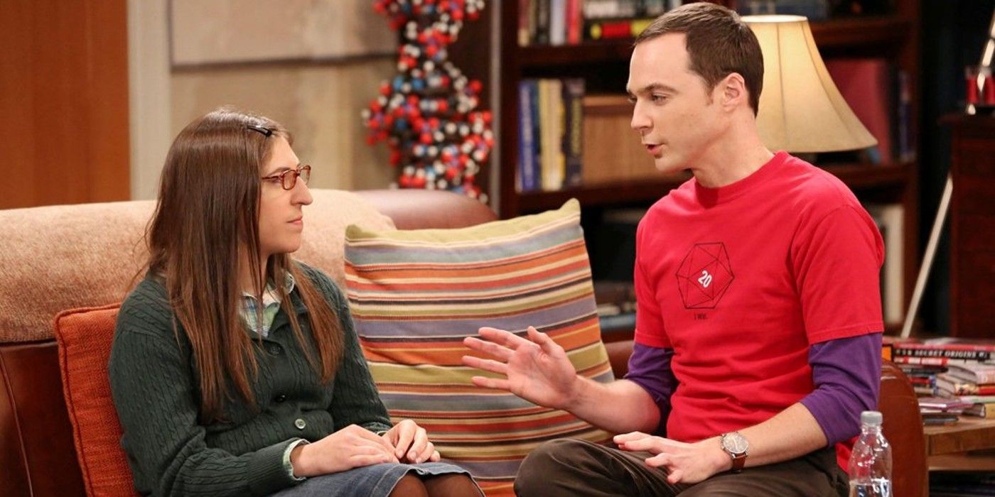 Amy and Sheldon sitting on the couch together in The Big Bang Theory