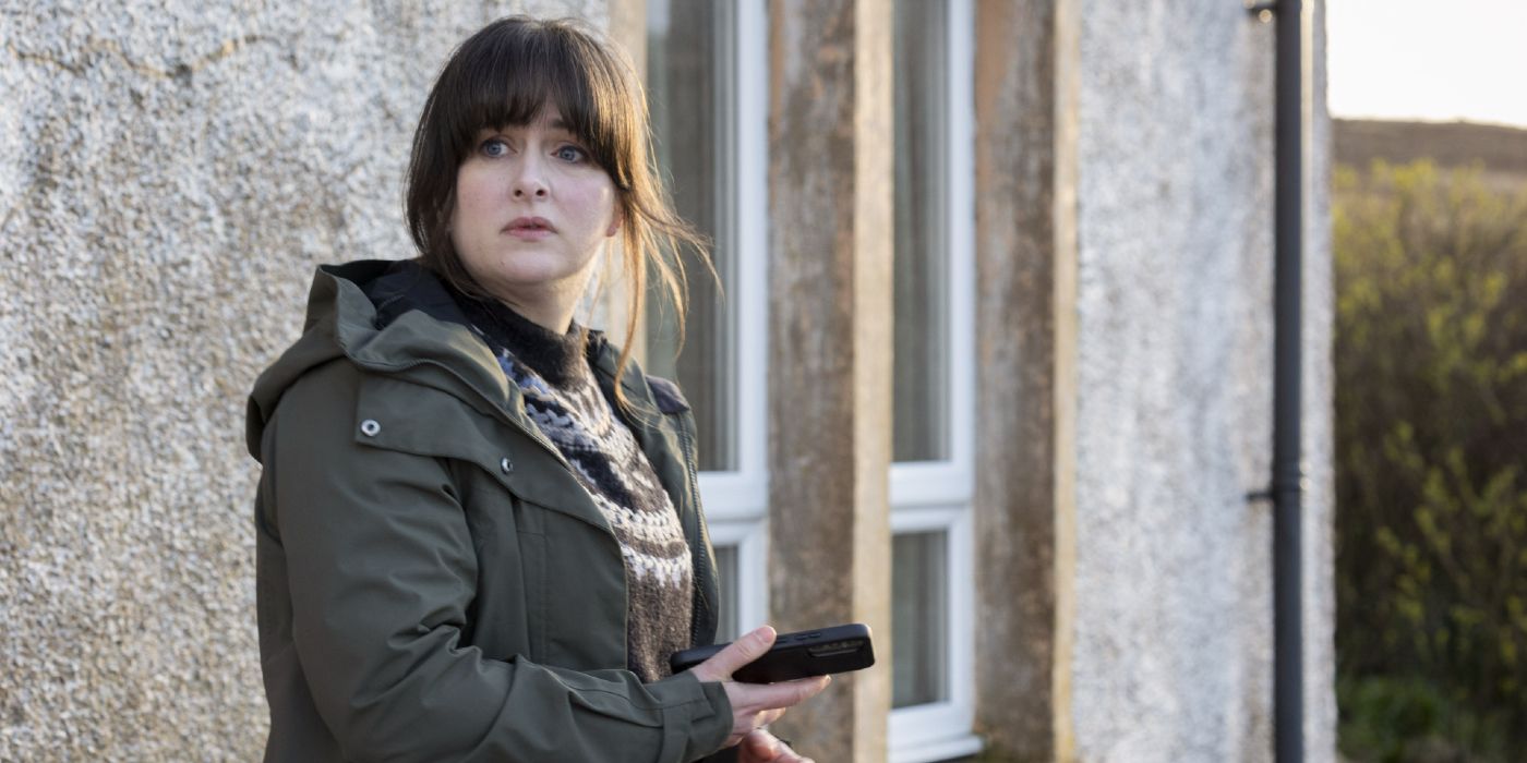 Alison O&rsquo;Donnell holding her phone as she spots something in the distance in Shetland Season 9