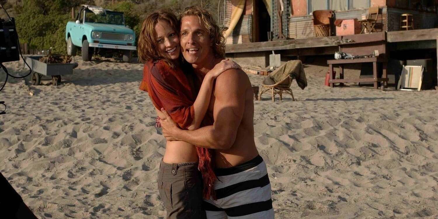 Matthew McConaughey as Steve Addington wearing a swimsuit on the beach and hugging a young woman in 'Surfer, Dude' (2008)